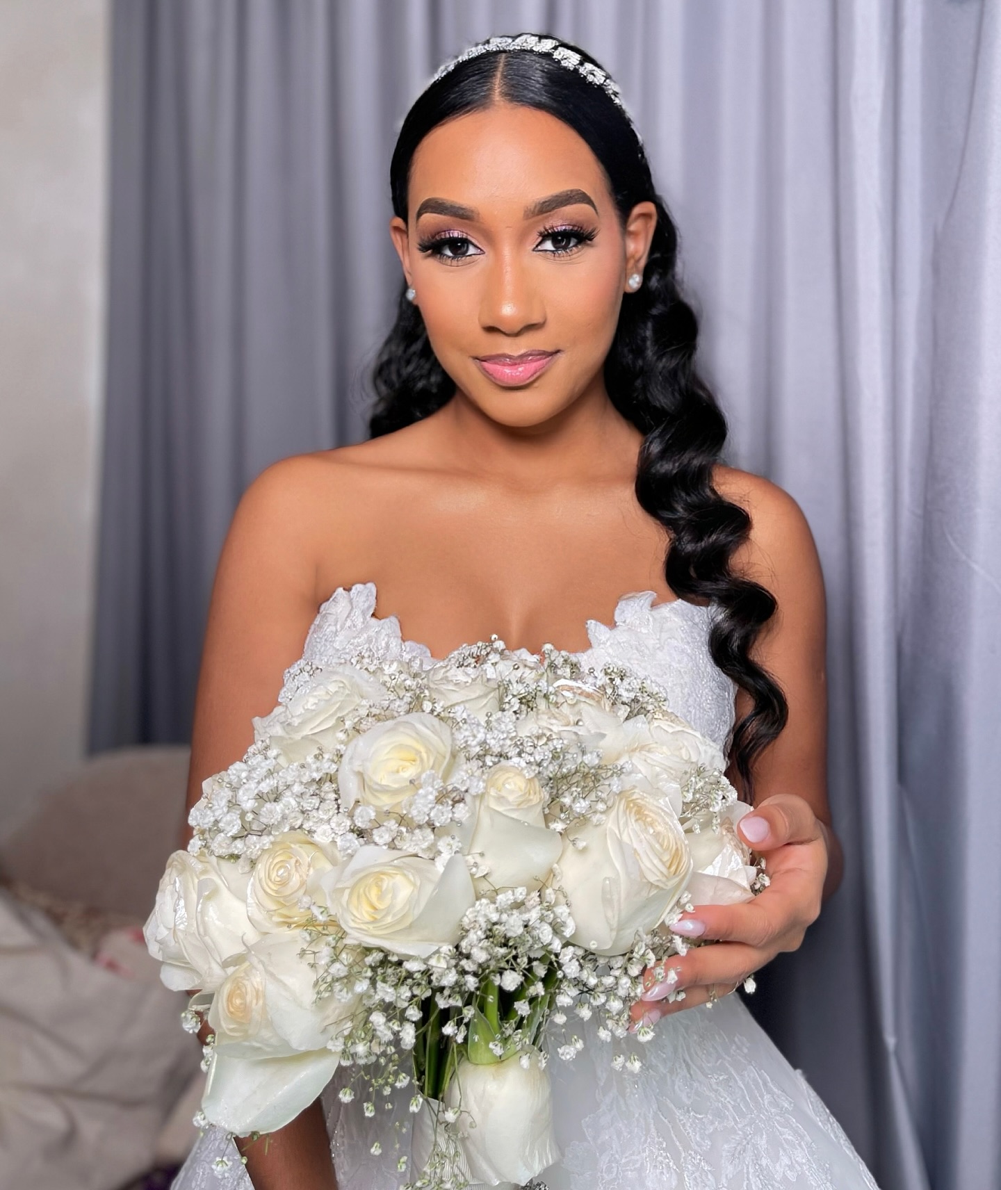 Noiva com penteado ondulado e buquê de rosas brancas